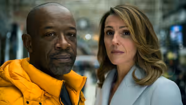 Nelly (Lennie James) and Claire (Suranne Jones) stand together in a busy indoor space