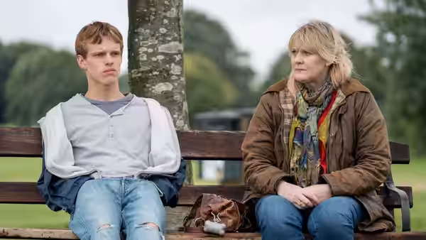 Miriam Grayson (Sarah Lancashire) sits beside a young man on a park bench