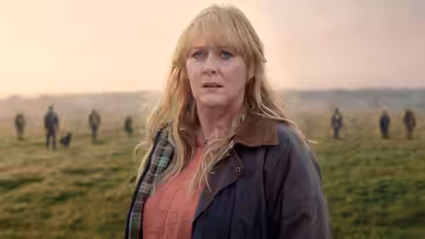 Miriam Grayson (Sarah Lancashire) stands in a field among people searching