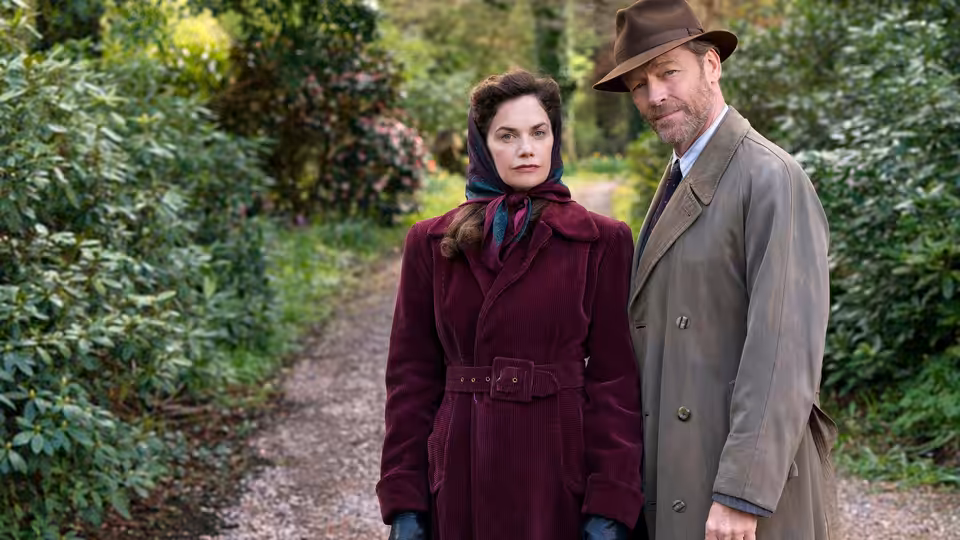 Alison Wilson (Ruth Wilson) and Alec Wilson (Iain Glen) stand together on a garden path