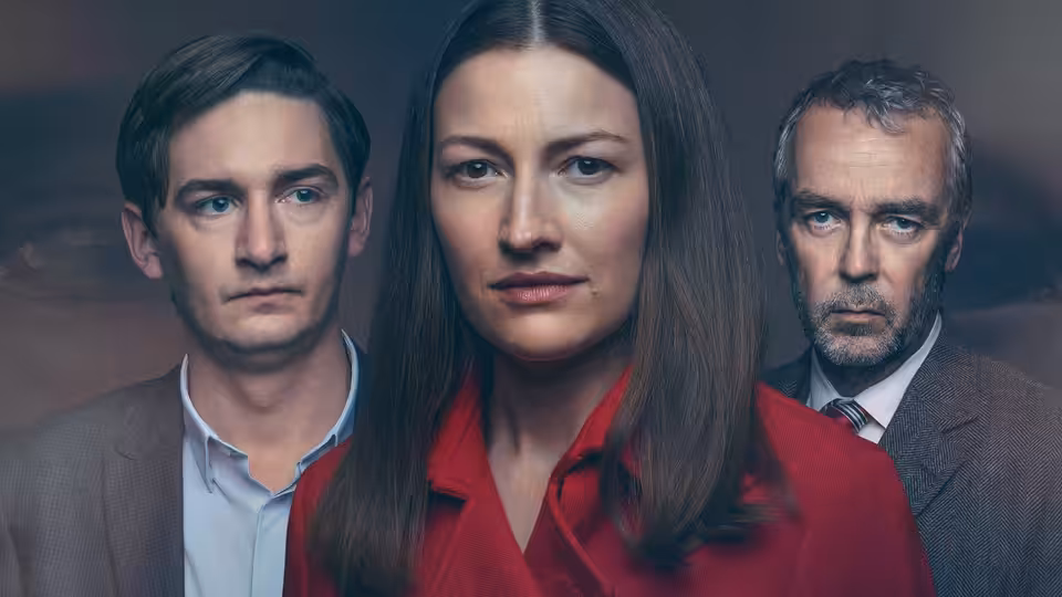 A woman in red stands between two men in suits against a dark background