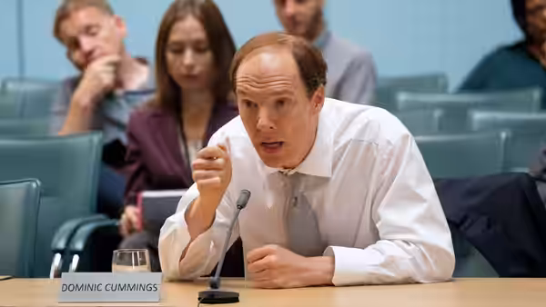 Dominic Cummings (Benedict Cumberbatch) speaks into a microphone at a parliamentary hearing