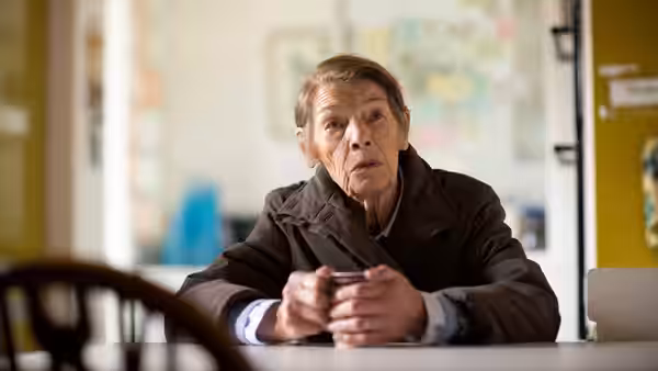 Maud Palmer Horsham (Glenda Jackson) sits at a table, clasping her hands