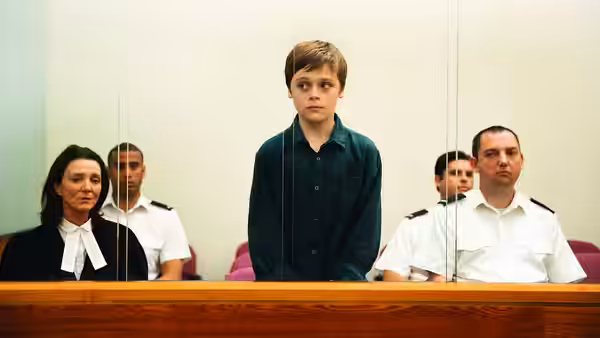 Ray (Billy Barratt) stands in court beside his barrister and seated officers