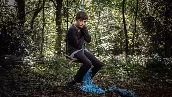 Ray (Billy Barratt) sits on a branch in the woods with a blue rope around him