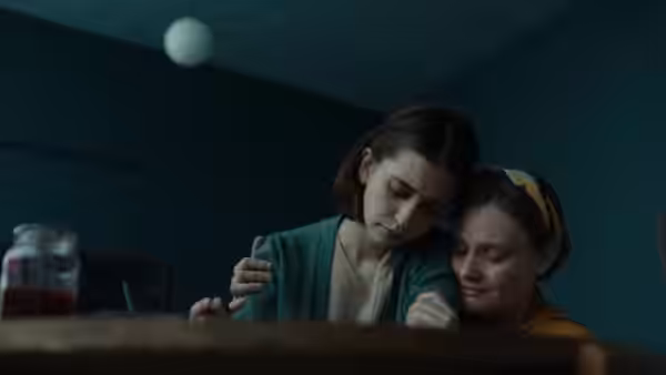 A young woman comforts another girl with an arm around her shoulders