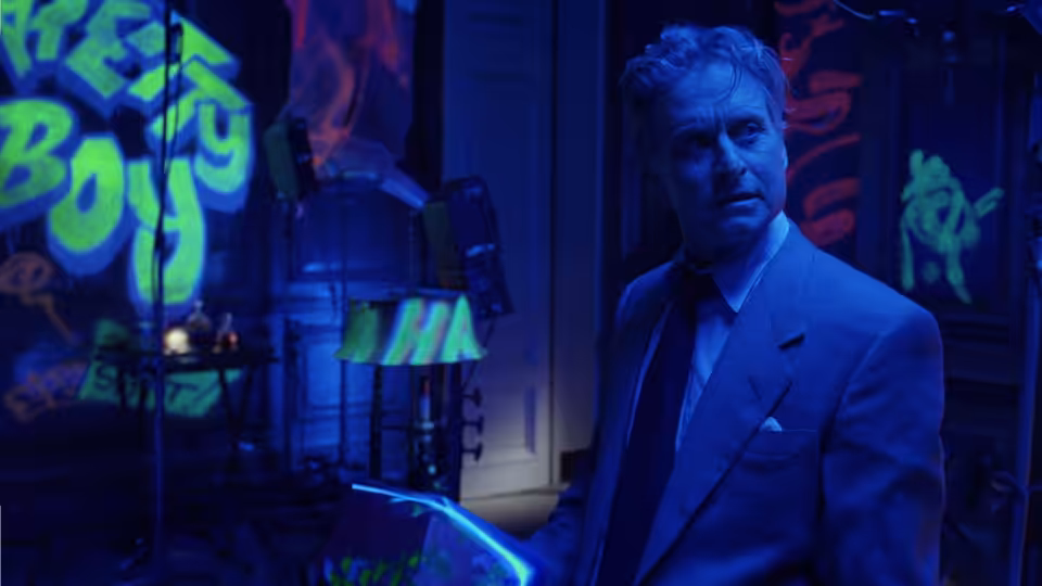 Nicholas Van Orton (Michael Douglas) stands amid neon signs and scattered equipment