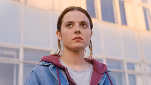 Bethan (Gabrielle Creevy) stands outside a modern building