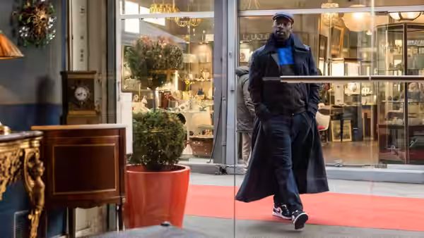 Assane Diop (Omar Sy) walks across a red carpet outside a shop