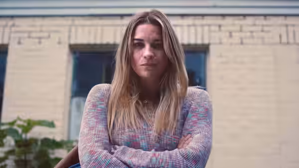 Allison McRoberts (Annie Murphy) stands with arms crossed outside a house