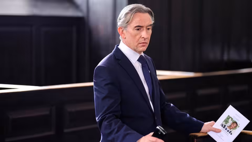 DCI Clive Driscoll (Steve Coogan) holds a document in a courtroom