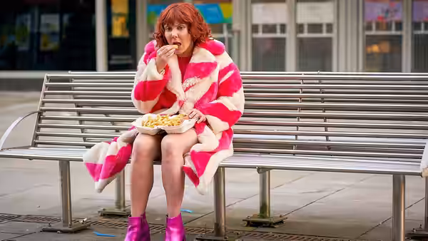 Alma (Sophie Willan) eats from a takeaway container on a bench
