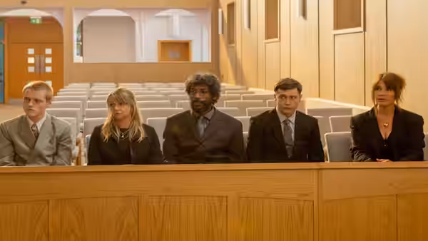 Five people sit behind a wooden barrier in a courtroom
