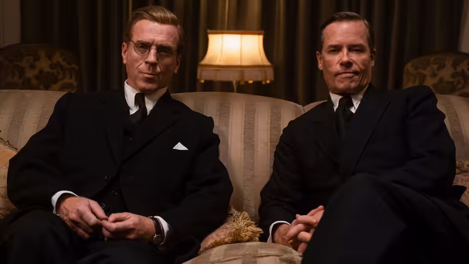 Kim Philby (Guy Pearce) and Nicholas Elliott (Damian Lewis) sit together on a sofa