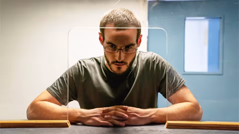 Ben Field (Éanna Hardwicke) leans over a table between two books