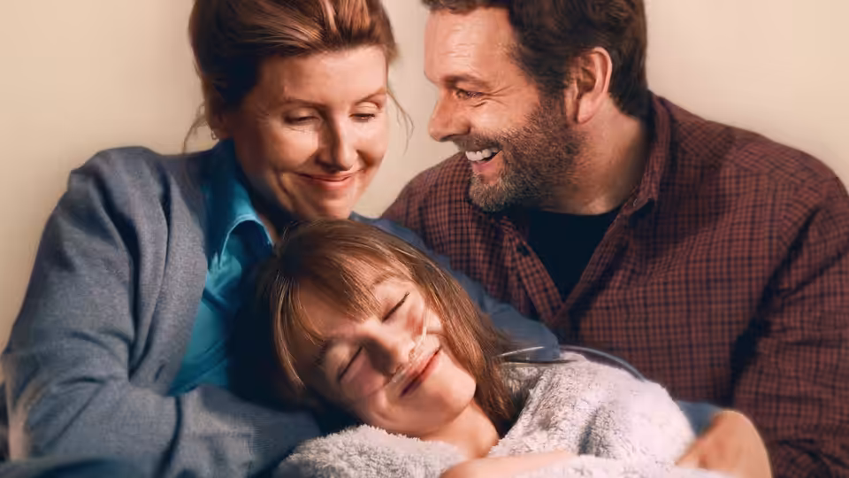 Nicci (Sharon Horgan) and Andrew (Michael Sheen) cuddle their daughter at home