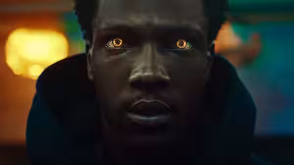 A young man stares ahead with glowing amber eyes