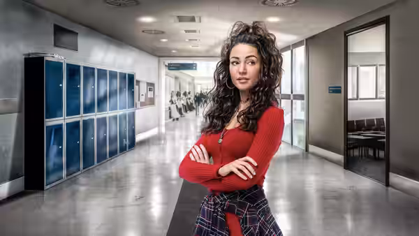 A woman stands with folded arms in a school corridor