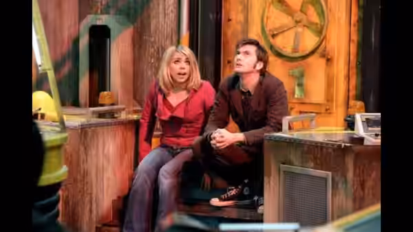 Rose Tyler (Billie Piper) and the Doctor (David Tennant) sit together in a cluttered room