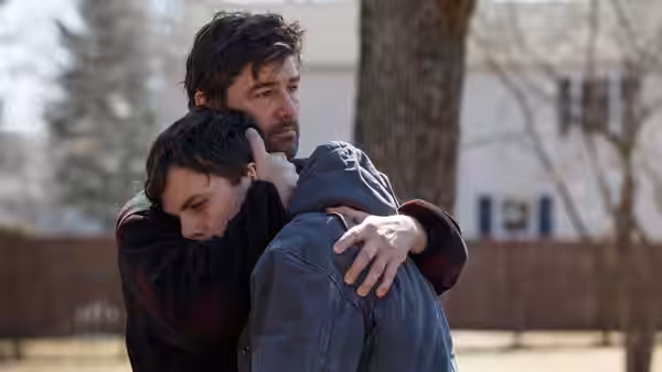 Lee Chandler (Casey Affleck) embraced by Joe Chandler (Kyle Chandler) outdoors