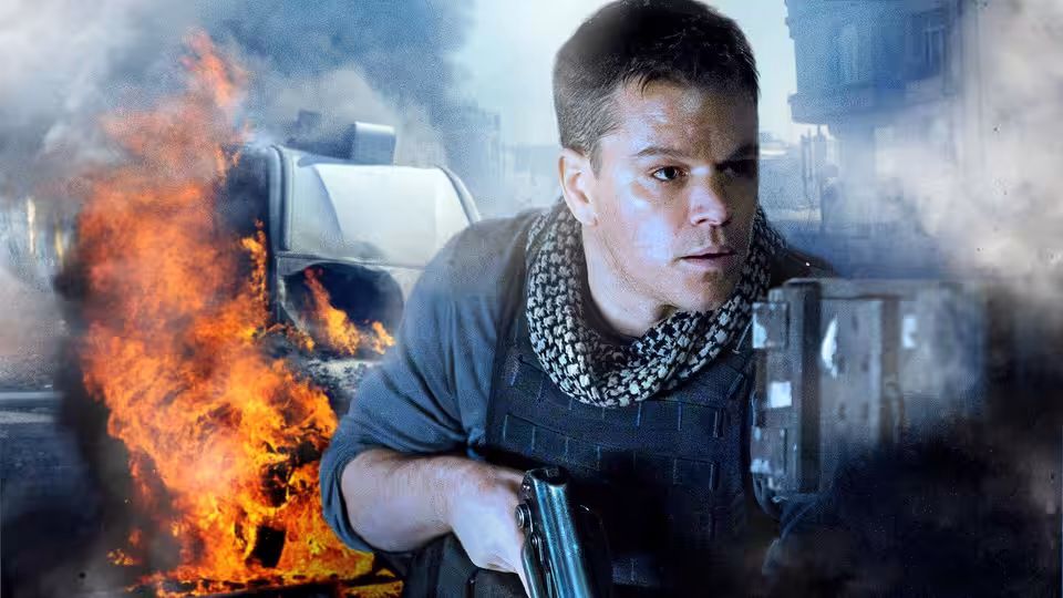 Roy Miller (Matt Damon) crouches with a rifle beside a burning vehicle