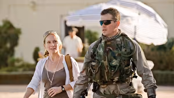 Roy Miller (Matt Damon) walks beside a woman in a sunlit courtyard