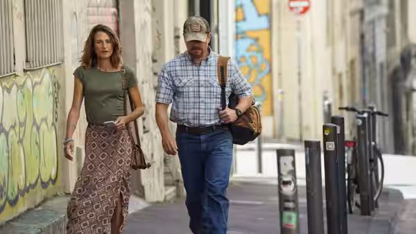 Virginie (Camille Cottin) and Bill Baker (Matt Damon) walk along a graffiti-lined street