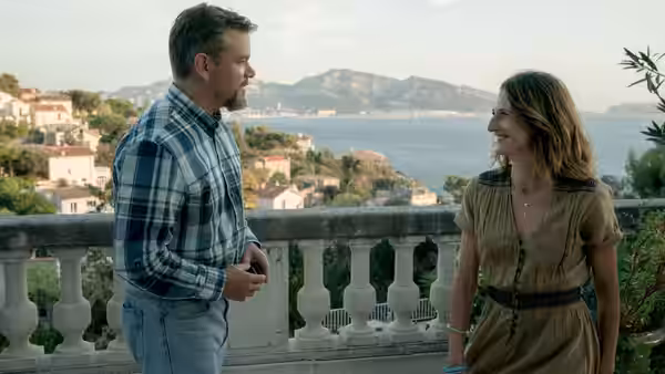 Bill Baker (Matt Damon) talks with Virginie (Camille Cottin) on a coastal terrace