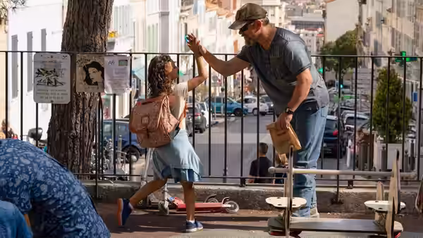 Bill Baker (Matt Damon) and Maya high-five beside a city sidewalk