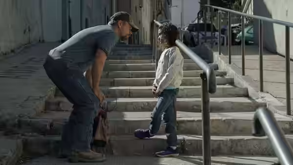 Bill Baker (Matt Damon) crouches beside Maya on a stone staircase