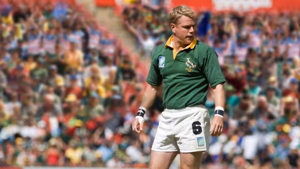 Francois Pienaar (Matt Damon) stands on the rugby field as spectators fill the stands