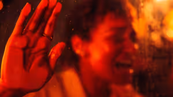 A crying woman presses her bloody hand against a glass surface