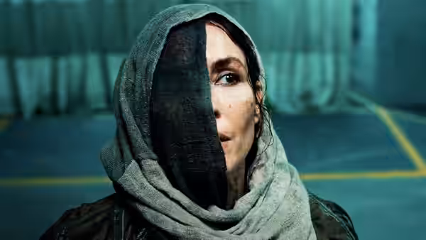 Rana (Noomi Rapace) in a headscarf looks aside in an industrial hall