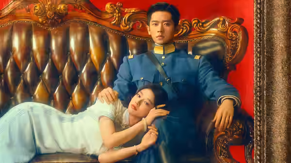 A uniformed man sits on a leather sofa as a woman reclines against him