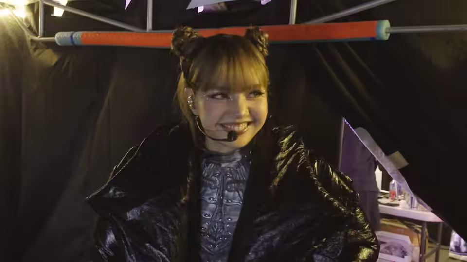 LISA (LISA) smiles backstage in a black robe with a headset microphone