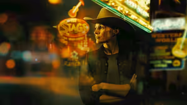 A cowboy-hatted woman stands with folded arms beneath glowing bar signs