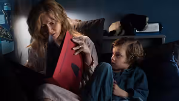 Amelia (Essie Davis) reading a red book to Samuel (Noah Wiseman) in bed