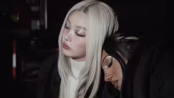 A blonde performer sits with her head resting against another woman