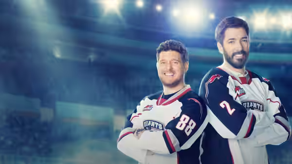 Two hockey players in Giants jerseys stand with arms crossed beneath arena lights