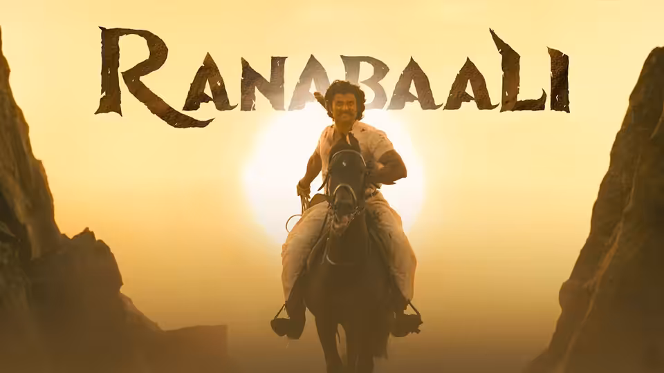 A mounted man rides through a narrow rocky pass against the setting sun