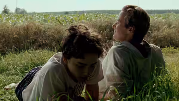Elio (Timothée Chalamet) and Oliver (Armie Hammer) lying together in a grassy field