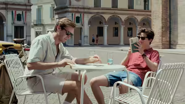 Oliver (Armie Hammer) and Elio (Timothée Chalamet) at a cafe table in a town square