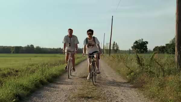Elio (Timothée Chalamet) and Oliver (Armie Hammer) riding bicycles on a country road