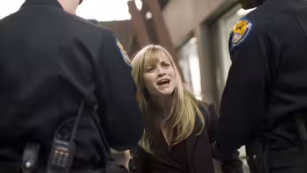 Isabella Fields El-Ibrahimi (Reese Witherspoon) cries out between two uniformed officers