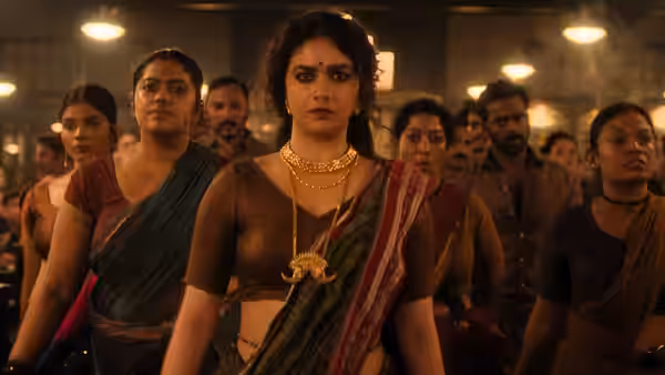 A woman in a sari walks forward with a group behind her