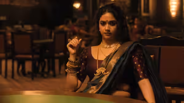 A woman in a sari sits at a table in a warmly lit room