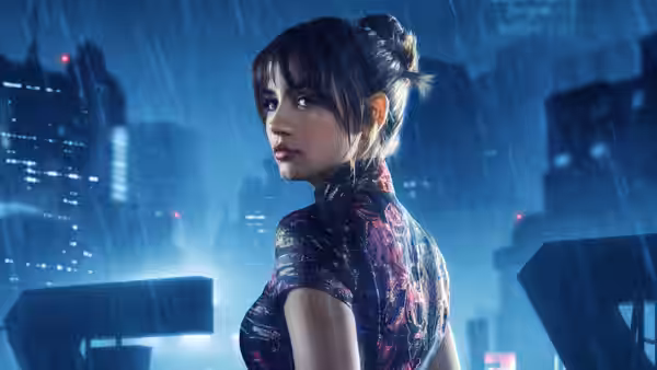 Joi (Ana de Armas) glances back while standing in a rainy neon street