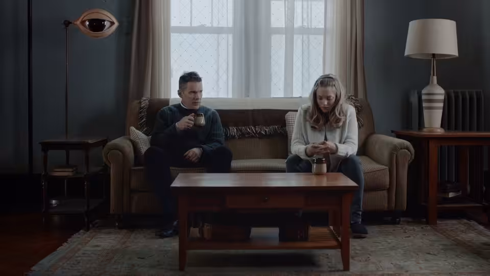 Pastor Toller (Ethan Hawke) and Mary (Amanda Seyfried) seated on a sofa
