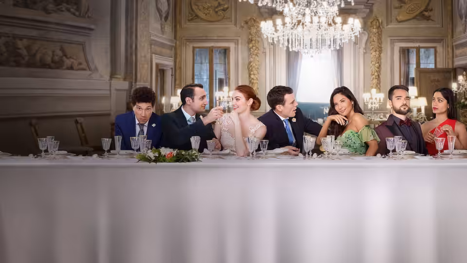 Wedding guests sit together at a long banquet table in an ornate reception hall