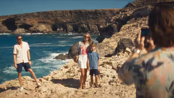 A woman photographs Anne (Stacy Martin) and a boy on a rocky shoreline as a man watches